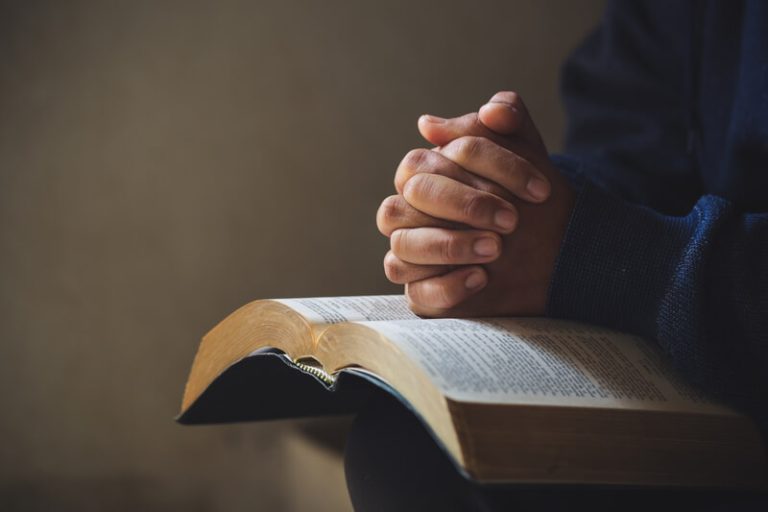 Hands folded in prayer on a Holy Bible in church concept for faith, spirituality and religion, woman praying on holy bible in the morning. woman hand with Bible praying