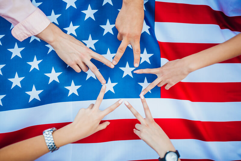 The hands of Americans against the background of the US flag. Independence Day