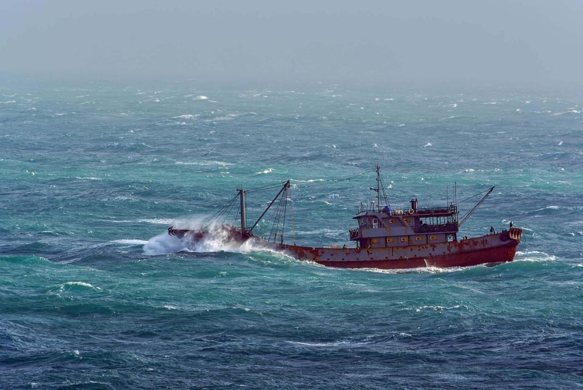 Fishing boat in rough weather. Small chinese trawler pounds through rough seas as it crosses the South China sea.