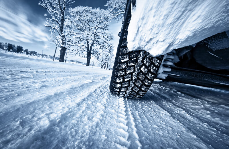 Car tires on winter road. Low angle view to car tires.