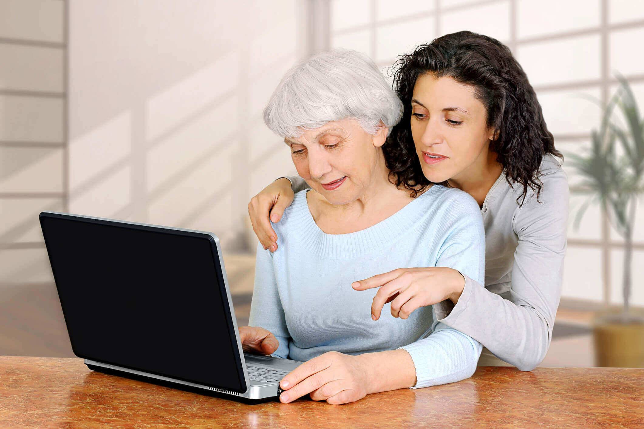 Young woman doctrine teaches daughter of an elderly woman laptop computer. Young women doctrine teaches daughter of an elderly women how to work using laptop computer at home