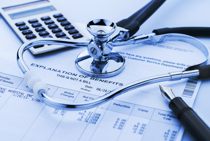 Figuring cost of health care and benefits with stethoscope and calculator in background