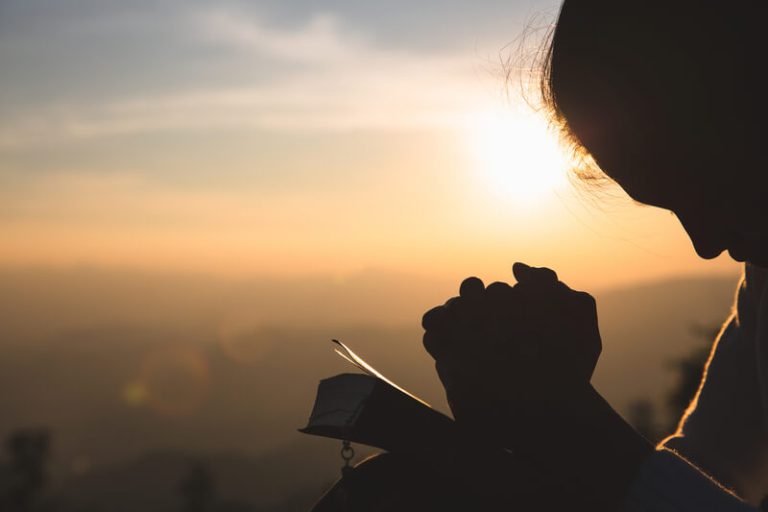 Woman praying in the morning on the sunrise background. Christianity concept. Pray background. Faith hope love concept.