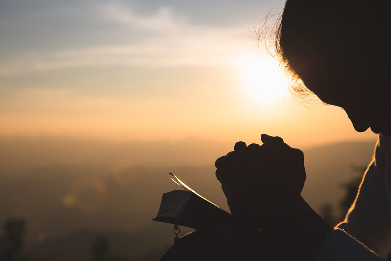 Woman praying in the morning on the sunrise background. Christianity concept. Pray background. Faith hope love concept.