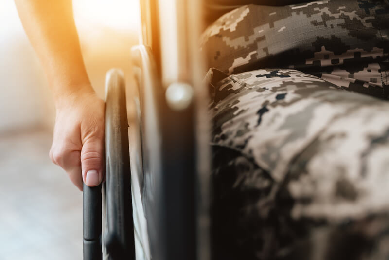 Woman veteran in wheelchair returned from army. Close-up photo veteran woman in a wheelchair. Wheelchairs and legs in military uniform.