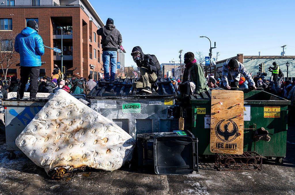 People gather on top of dumpsters at the intersection of 26th Street and Nicollet Avenue after a fatal shooting by federal agents on January 24, 2026 in Minneapolis, Minnesota.