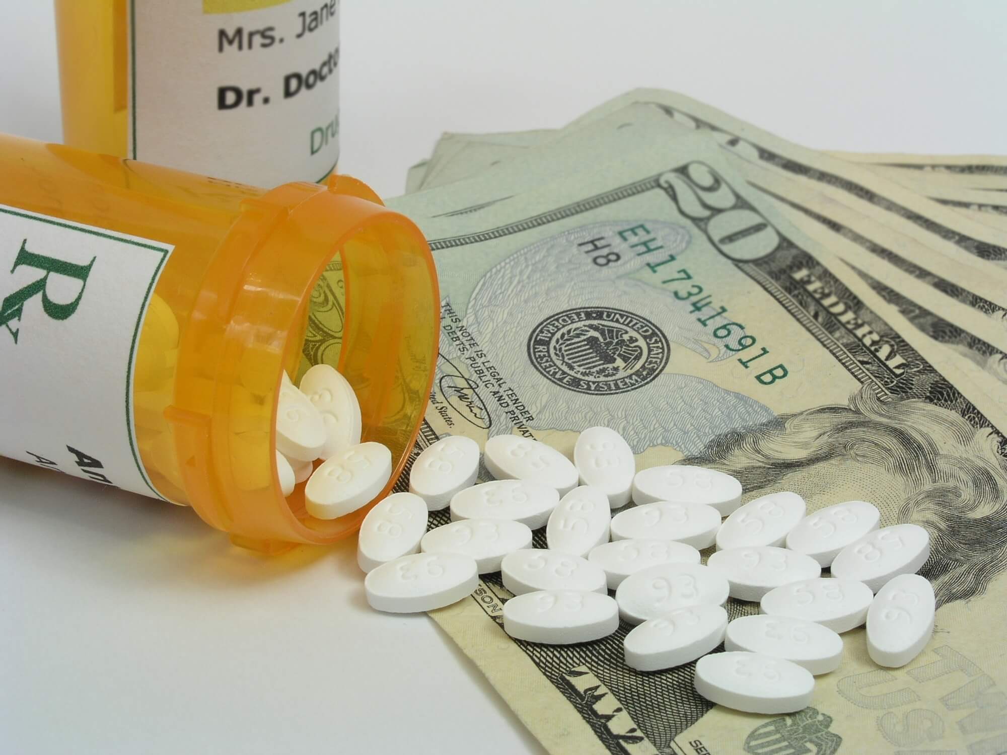 High Cost of Prescription Drugs. Bottle of presecription medication, spilling out onto a stack of twenty dollar bills.
