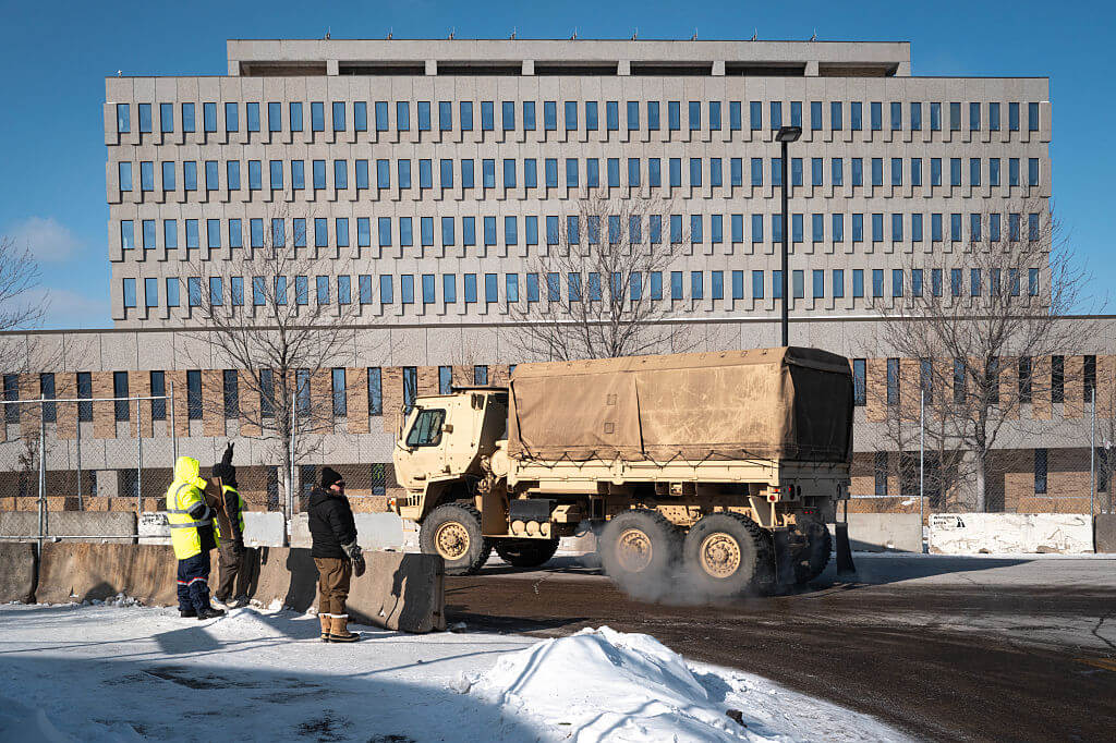 MINNEAPOLIS, MINNESOTA - JANUARY 25: Demonstrators protest outside of the Whipple federal building as an Army National guard vehicle drives past on January 25, 2026 in Minneapolis, Minnesota. Yesterday Minnesota Governor Tim Walz called out the guard after federal immigration agents shot and killed Alex Pretti, an ICU nurse at a VA medical center, during a brief altercation in the Eat Street district of Minneapolis. (Photo by Scott Olson/Getty Images)