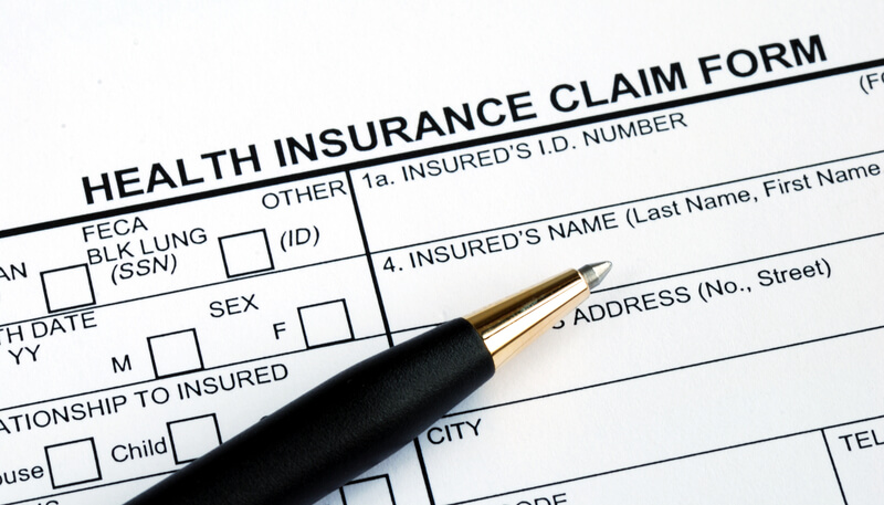 Filling the health insurance claim form with a pen