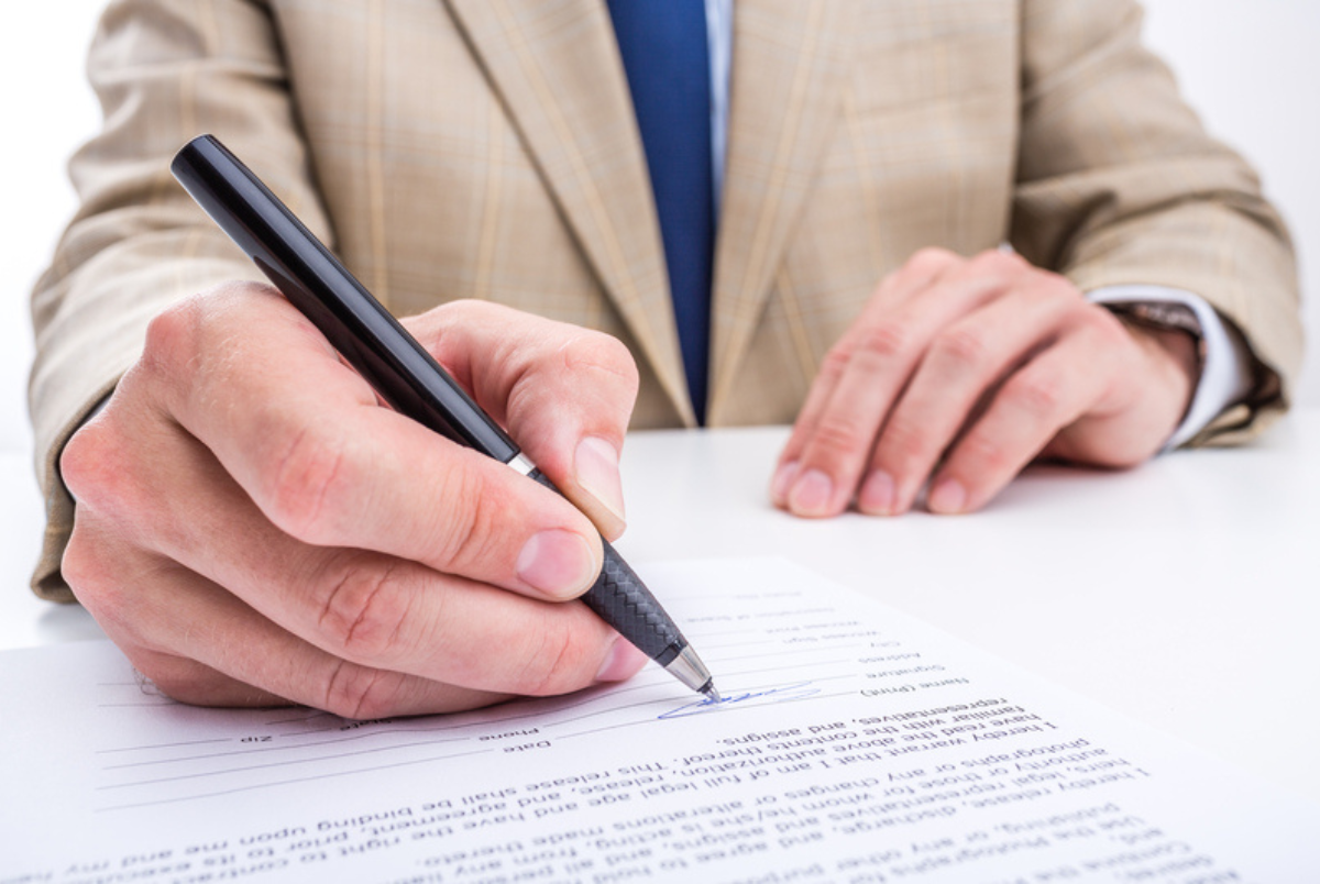 Man in sports jacket signing Medigap paperwork.