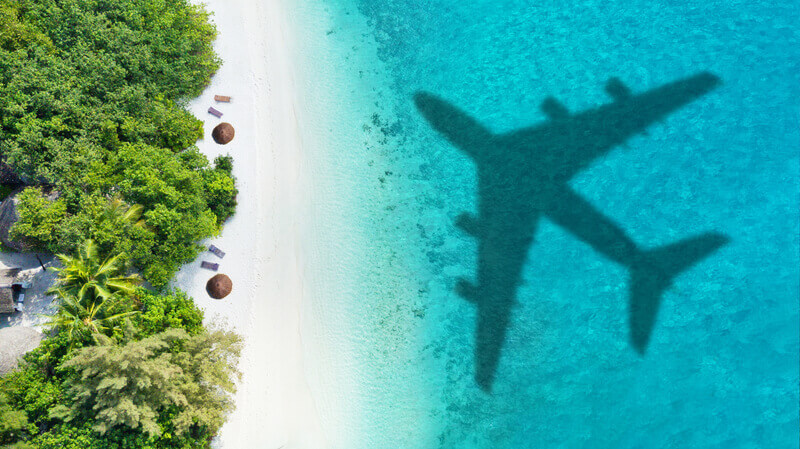 Travel concept with airplane shadow and beach. Tropical paradise and beach holiday conceptual image.