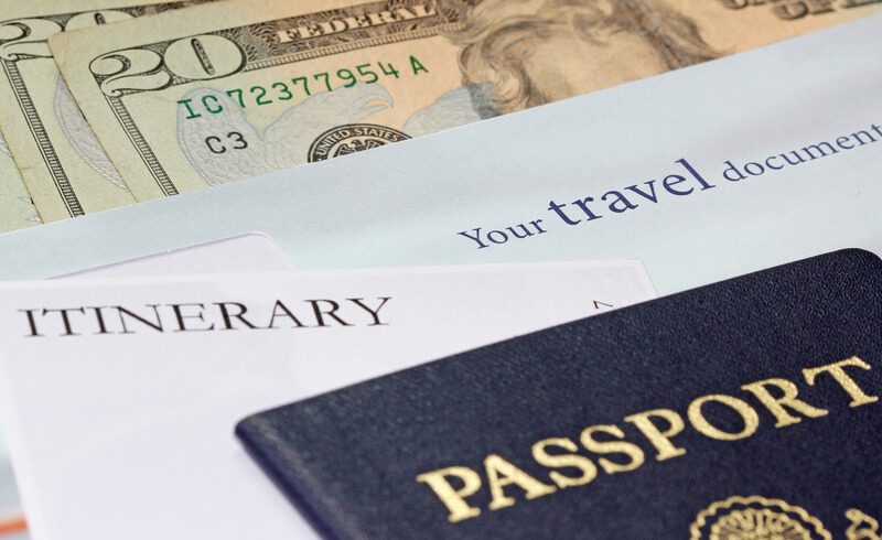 A spread of international travel necessities including a passport, itinerary, money and other travel documents.