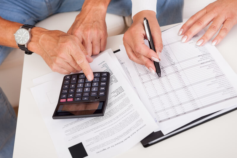 Excited middle-aged couple doing finances at home. Excited middle-aged couple sitting on a couch reading a document together which contains good news