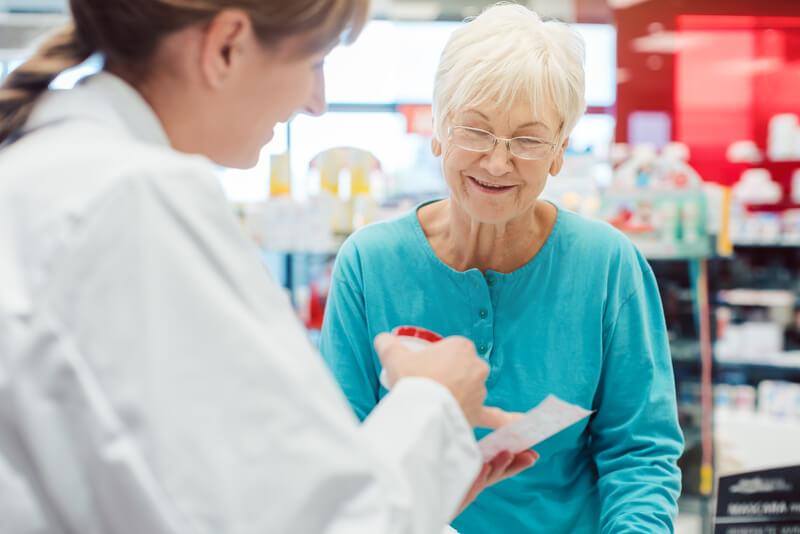 Senior woman in pharmacy talking to the chemist or pharmacist. Senior women in pharmacy talking to the chemist or pharmacist explain effects of a drug