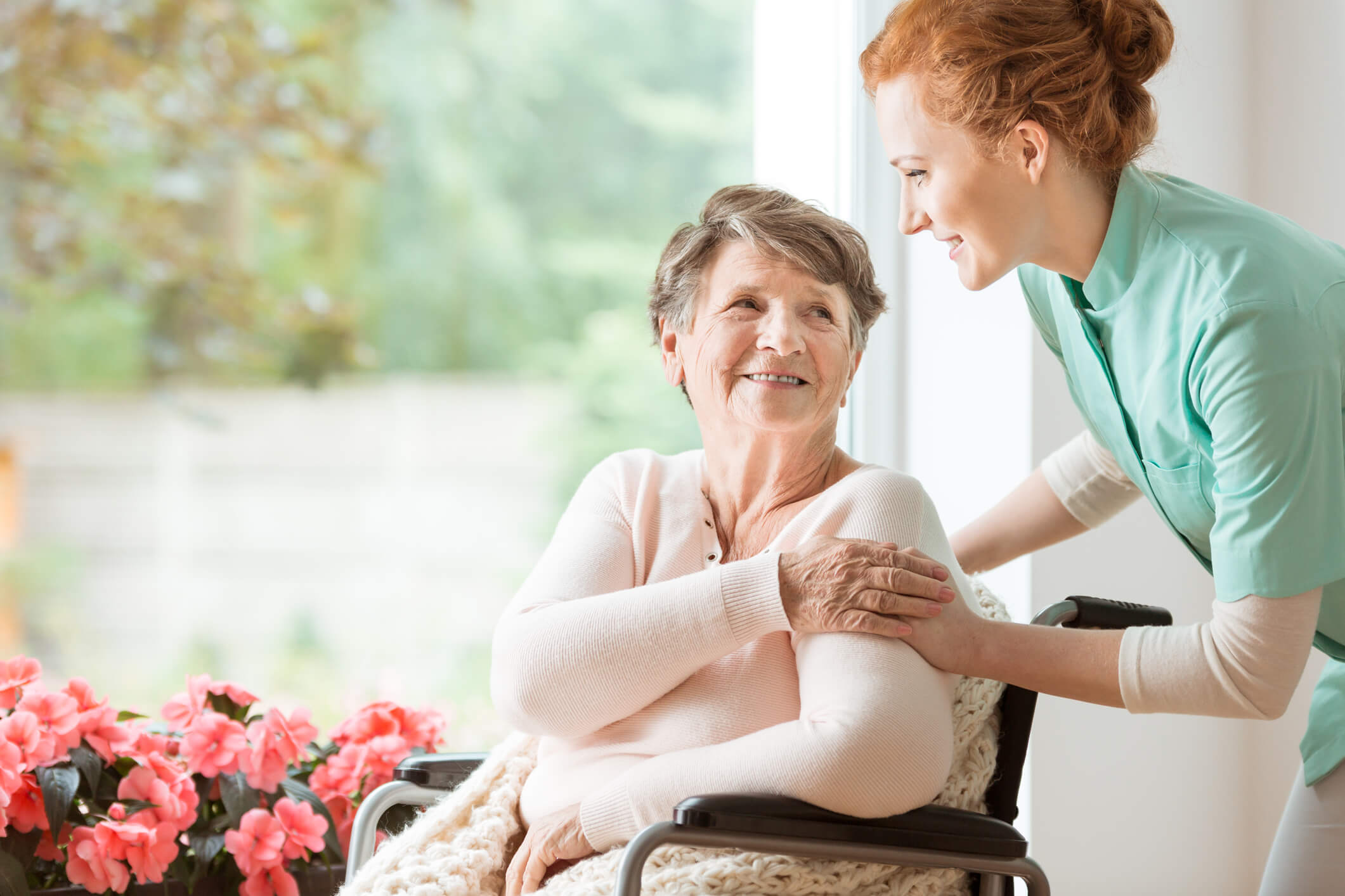 Young nurse helping an elderly woman in a wheelchair. Nursing ho. Nursing home concept.