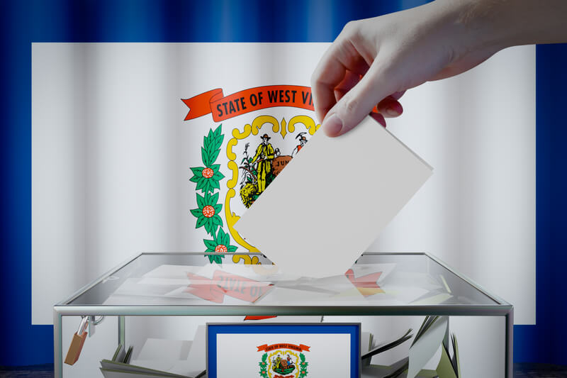 West Virginia flag, hand dropping ballot card into a box