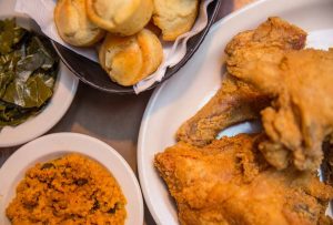 A meal of crispy Southern-style fried chicken served with sides of collard greens and cornbread muffins.