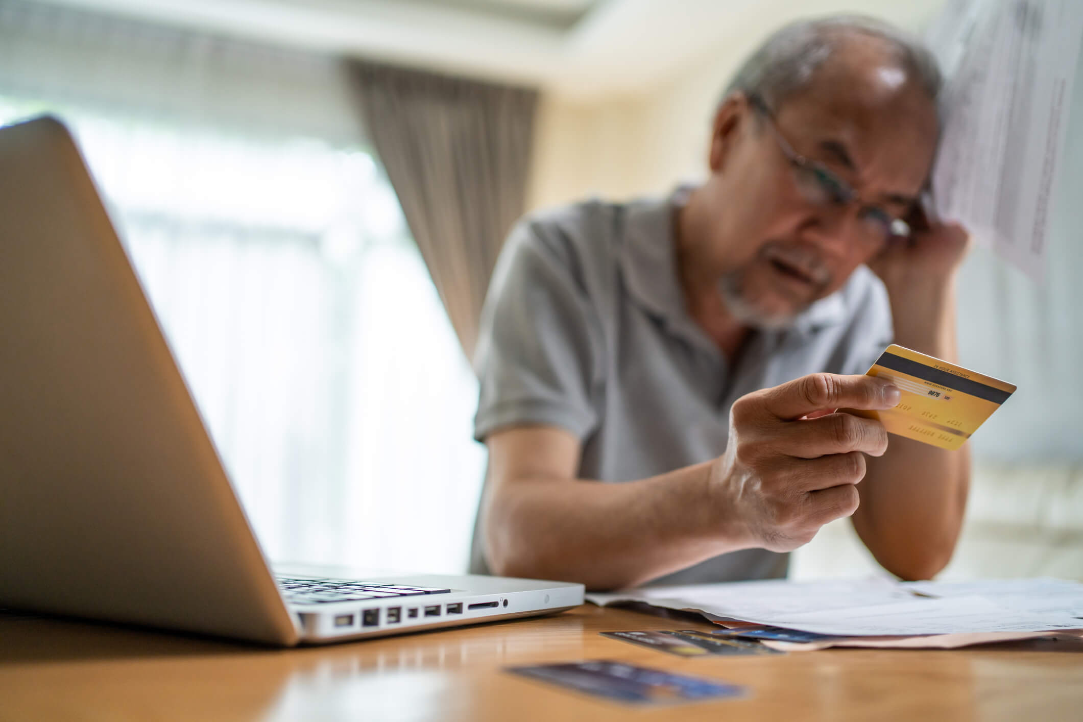 Depressed Asian Senior male feeling worried about financial problem. Stressed desperate elderly older man looking frustrated to paperwork and bills think of money debt, budget loss, bankruptcy at home