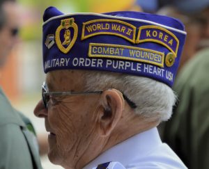 Veteran Wears Decorative Hat with Patches. WWII and Korean War veteran proudly wears a hat with patches displaying his military service: combat wounded, purple heart.
