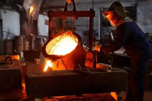 Molten metal is being poured from a furnace or ladle into a mold to create new components.