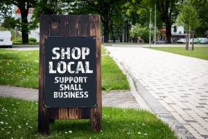 Shop Local. Support small business. Wooden billboard on the street, sunny day.
