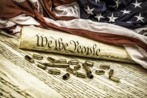 Constitution and bullets. The United States Constitution rolled up on an American flag with bullets scattered about symbolizing the second amendment.