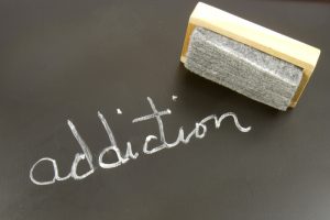 Erasing Addiction. The word ADDICTION written on a chalkboard with an eraser