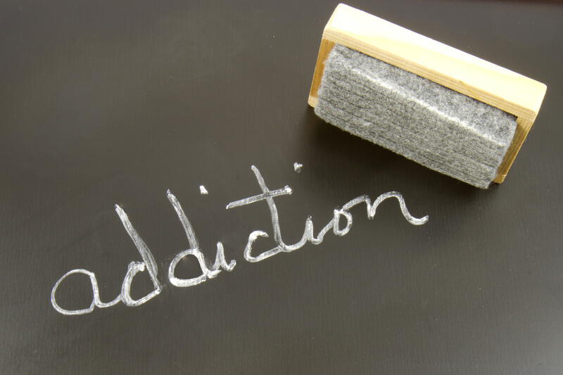 Erasing Addiction. The word ADDICTION written on a chalkboard with an eraser
