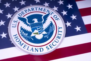 The symbol of the US Department of Homeland Security pictured over the USA Flag