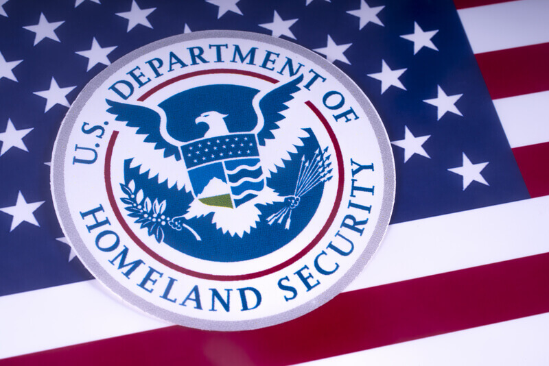 The symbol of the US Department of Homeland Security pictured over the USA Flag