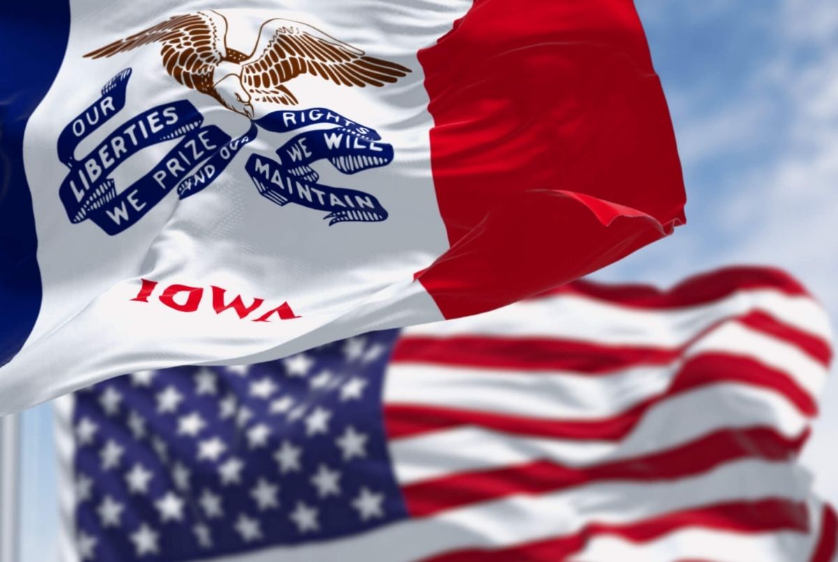 Close-up of Iowa state flag waving in the wind with the US flag on a clear day. Close-up of Iowa state flag waving in the wind with the American national flag on a clear day. 3d illustration render. Rippled fabric. Selective focus