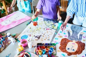 Hands of Children Painting in Art Class. High angle of unrecognizable children painting pictures with watercolors working together in art studio