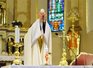 Catholic Mass - holly sacrifice of blood and body of Jesus Christ in lanscape orientation photo, focused to hands of priest
