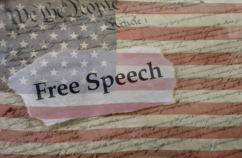 Free Speech, Constitution and flag. Free Speech news headline on a copy of the United States Constitution and the US flag