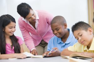 Elementary school classroom. Teacher helping elementary school reading group