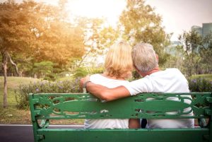 Senior couple siting on a bench and having romantic and relaxing time in a park, back view