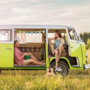 A Volkswagen Type 2, also famously known as the Volkswagen Bus or Kombi. This specific model is a lime green and white vintage variant, often associated with road trips, camping, and "van life" culture.