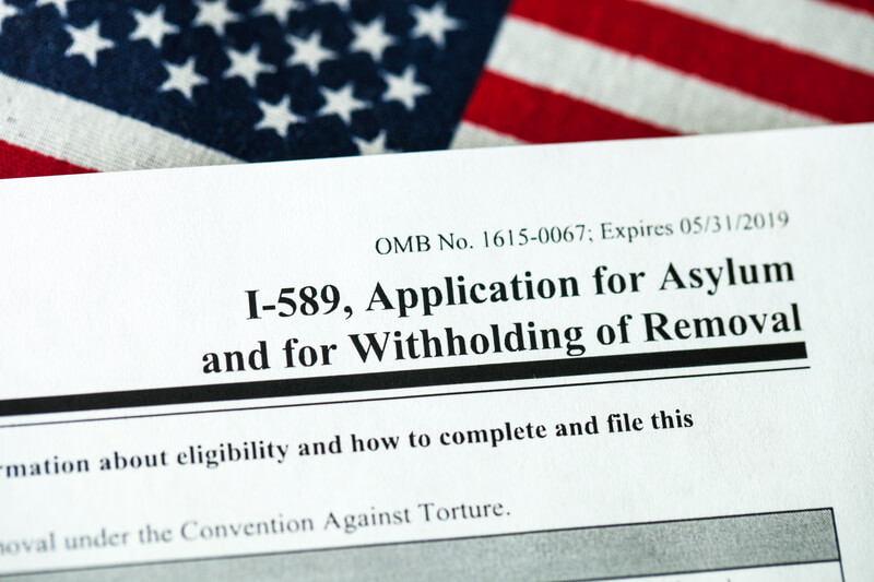 Application for asylum to USA concept with application form and USA Flag in the background.