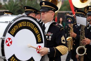 A soldier from the Eighth United States Army Band playing a bass drum during a parade.