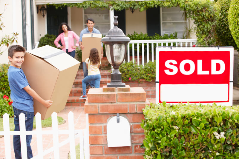 Family moving into new home carrying boxes