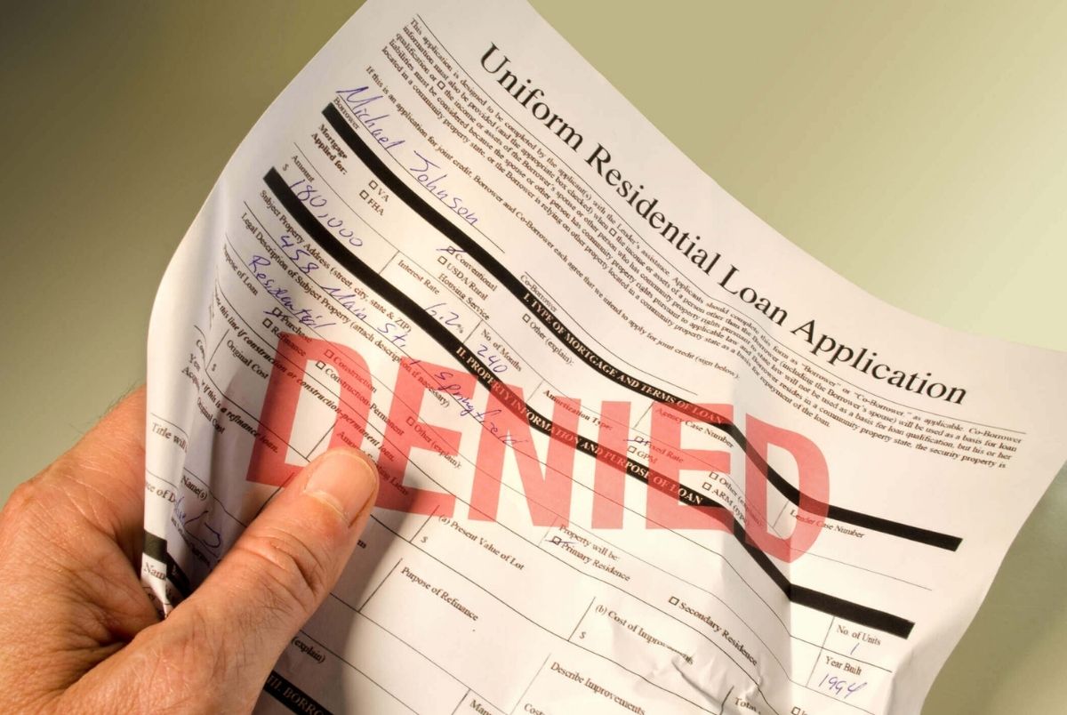 Denied loan application crumpled in hand. Denied loan application crumpled in the hand of upset man because he was denied the loan for a house. All information on the application is fictitious.