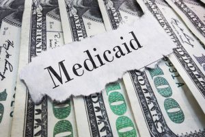 Medicaid headline. Medicaid torn newspaper headline on cash