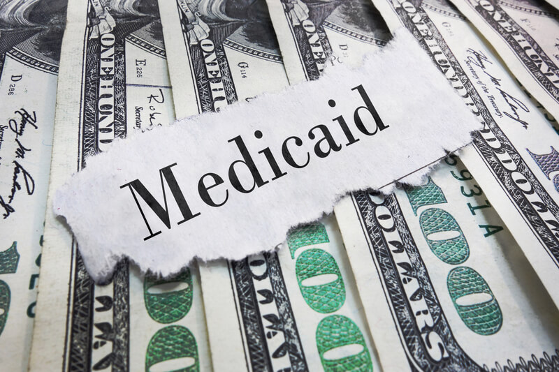 Medicaid headline. Medicaid torn newspaper headline on cash