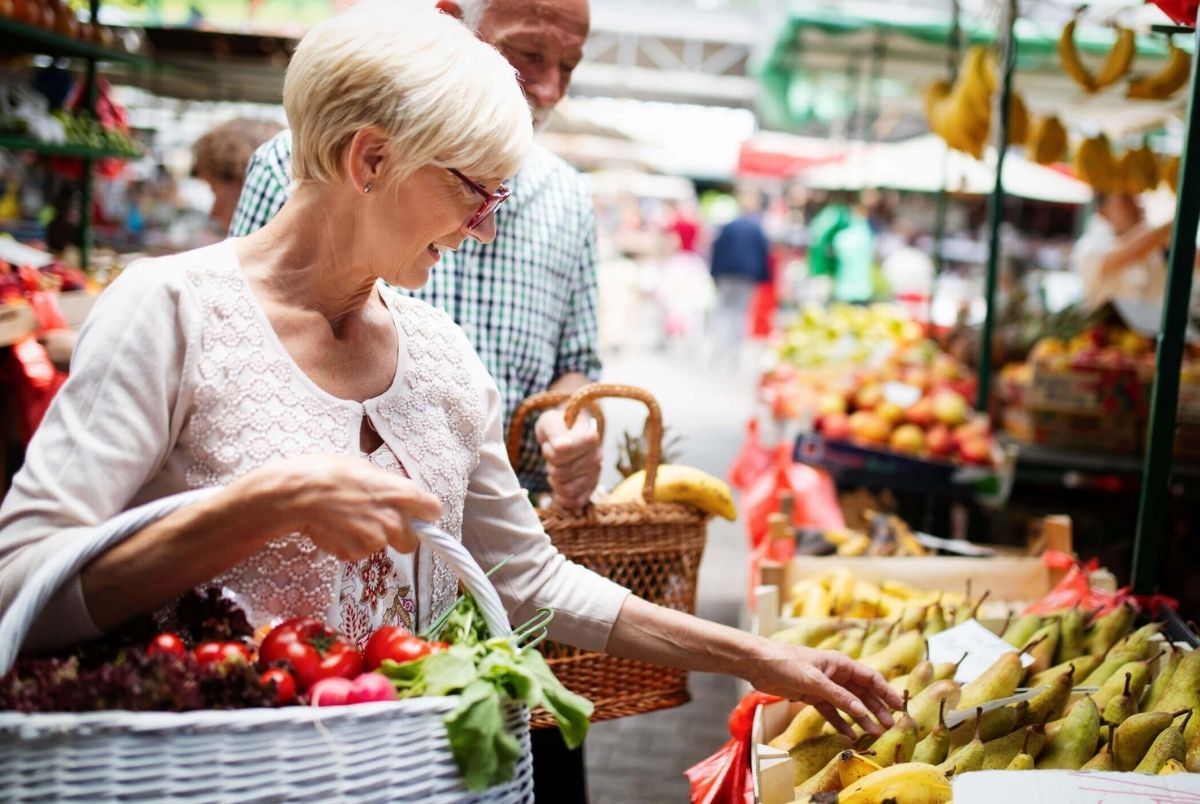 Mature woman buying vegetables at farmers market. Senior women buying vegetables at farmers market