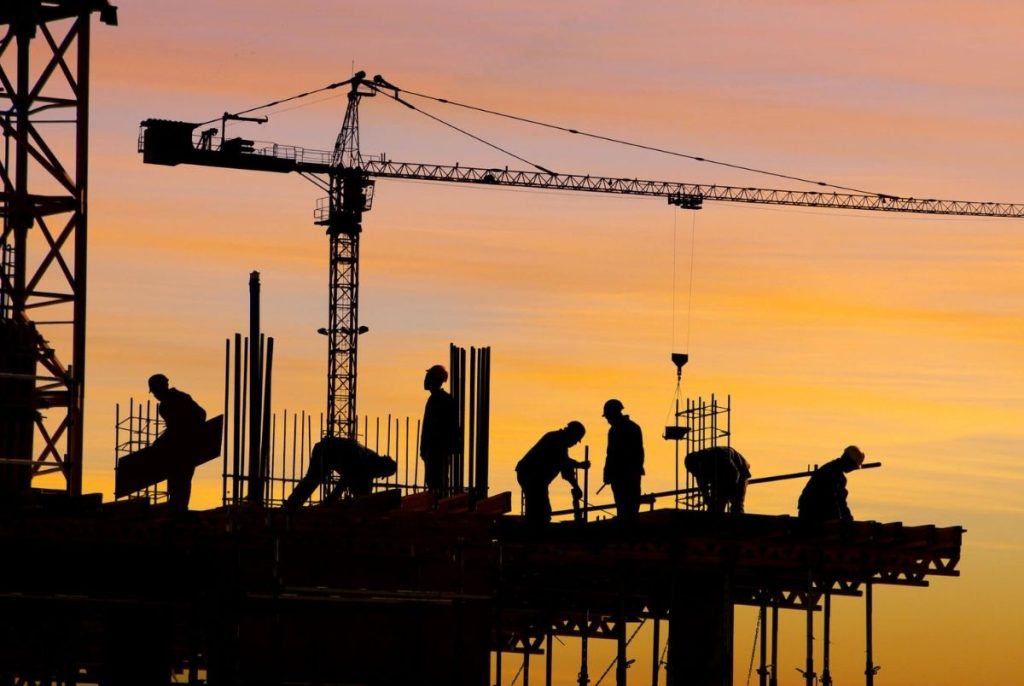 Construction site silhouette. Silhouette of hardworking men on construction site at sunset