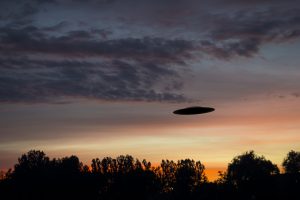 UFO sighting. A UFO is fliing over the trees.