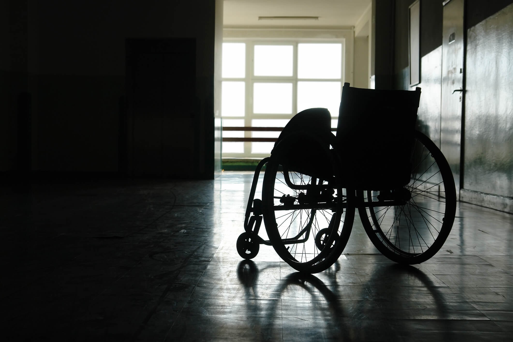 Silhouette of empty wheelchair parked in hospital hallway