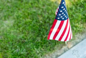 A single American flag placed at a veteran`s gravesite marker for Memorial Day