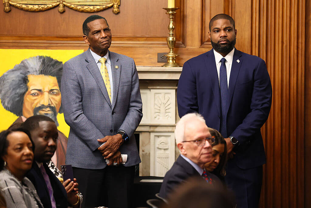 Rep. Burgess Owens (R-UT) and Rep. Byron Donalds (R-FL) listen as House Speaker Mike Johnson (R-LA) speaks in the Rayburn Reception Room after formally unveiling the Frederick Douglass Press Gallery in the US Capitol on February 12, 2026 in Washington, DC.