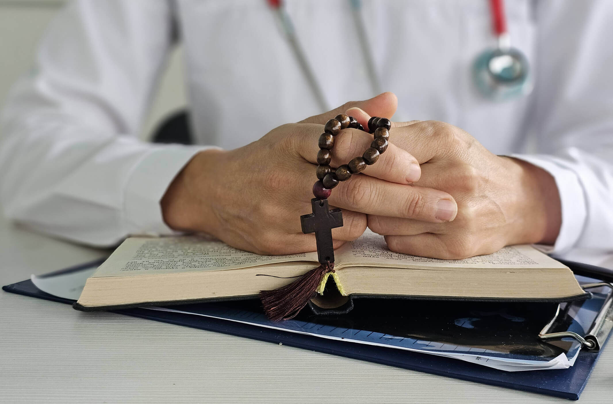 A medical worker holds a rosary with a cross and meditates. The relationship between religion and medicine. Orthodoxy and medicine.